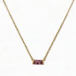 A February Birthstone Amethyst Cubic Zirconia Baguette Necklace by Skōsh Jewelry, featuring a slim rectangular purple baguette stone set horizontally on a fine gold chain, displayed against a white background.