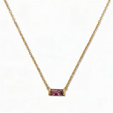 A February Birthstone Amethyst Cubic Zirconia Baguette Necklace by Skōsh Jewelry, featuring a slim rectangular purple baguette stone set horizontally on a fine gold chain, displayed against a white background.
