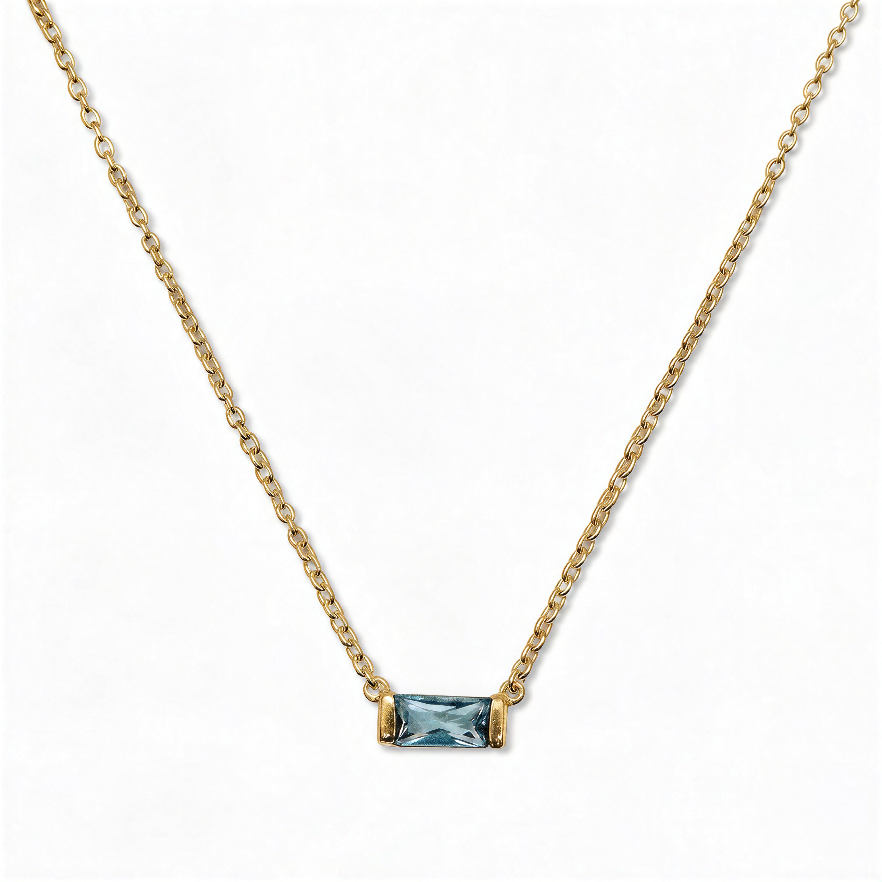 A March Birthstone Light Sapphire Cubic Zirconia Baguette Necklace by Skōsh Jewelry, featuring a slim rectangular light blue baguette stone set horizontally on a fine gold chain, displayed against a white background.
