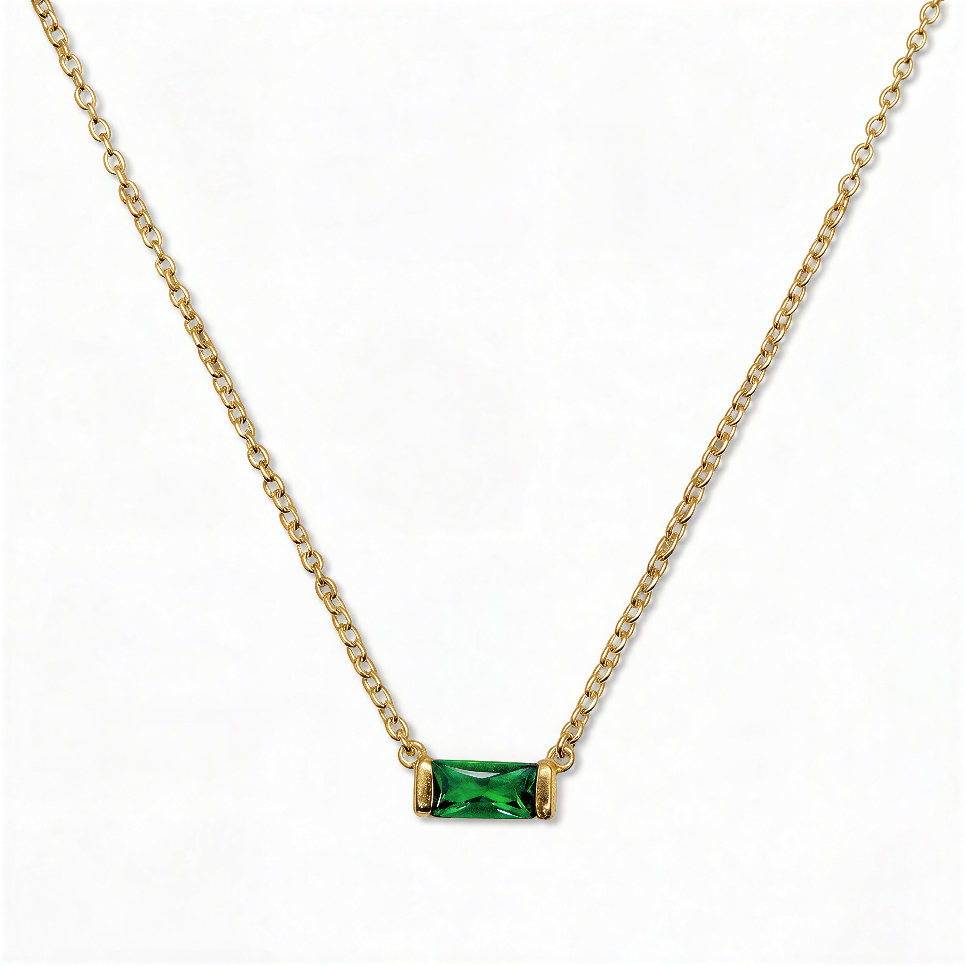 A May Birthstone Emerald Cubic Zirconia Baguette Necklace by Skōsh Jewelry, featuring a slim rectangular green baguette stone set horizontally on a fine gold chain, displayed against a white background.