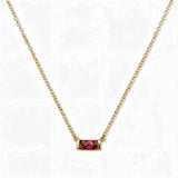 A July Birthstone Ruby Cubic Zirconia Baguette Necklace by Skōsh Jewelry, featuring a slim rectangular red baguette stone set horizontally on a fine gold chain, displayed against a white background.