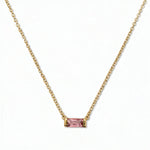 An October Birthstone Pink Cubic Zirconia Baguette Necklace by Skōsh Jewelry, featuring a slim rectangular pink baguette stone set horizontally on a fine gold chain, displayed against a white background.
