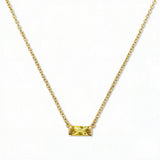 A November Birthstone Citrine Cubic Zirconia Baguette Necklace by Skōsh Jewelry, featuring a slim rectangular yellow baguette stone set horizontally on a fine gold chain, displayed against a white background.