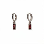 A pair of January Birthstone Garnet Cubic Zirconia Baguette Earrings by Skōsh Jewelry, featuring small sterling silver huggie hoops, each with a rectangular deep red baguette stone dangling below, displayed against a white background.