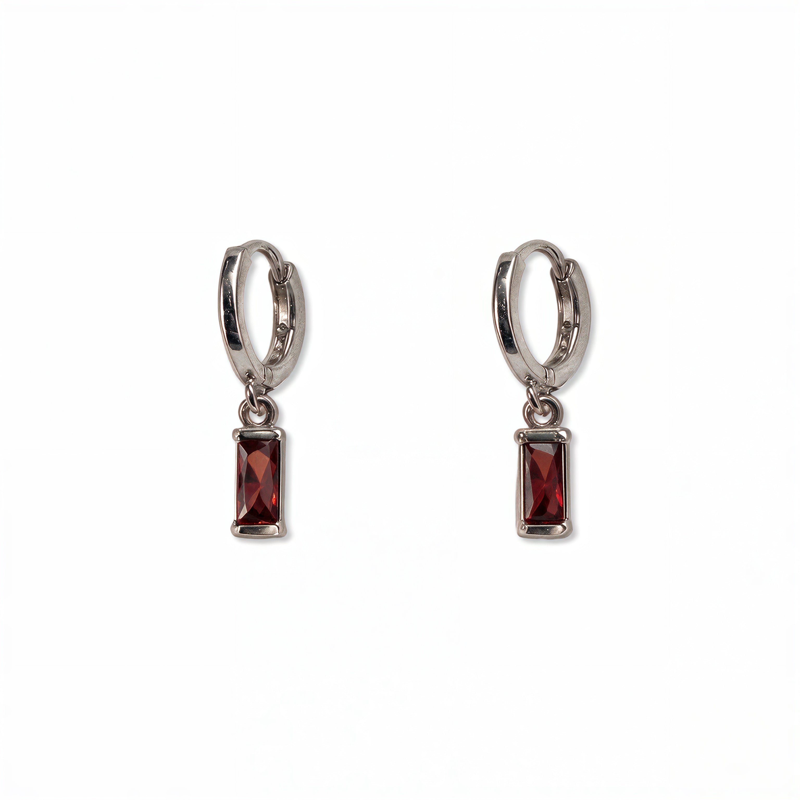 A pair of January Birthstone Garnet Cubic Zirconia Baguette Earrings by Skōsh Jewelry, featuring small sterling silver huggie hoops, each with a rectangular deep red baguette stone dangling below, displayed against a white background.