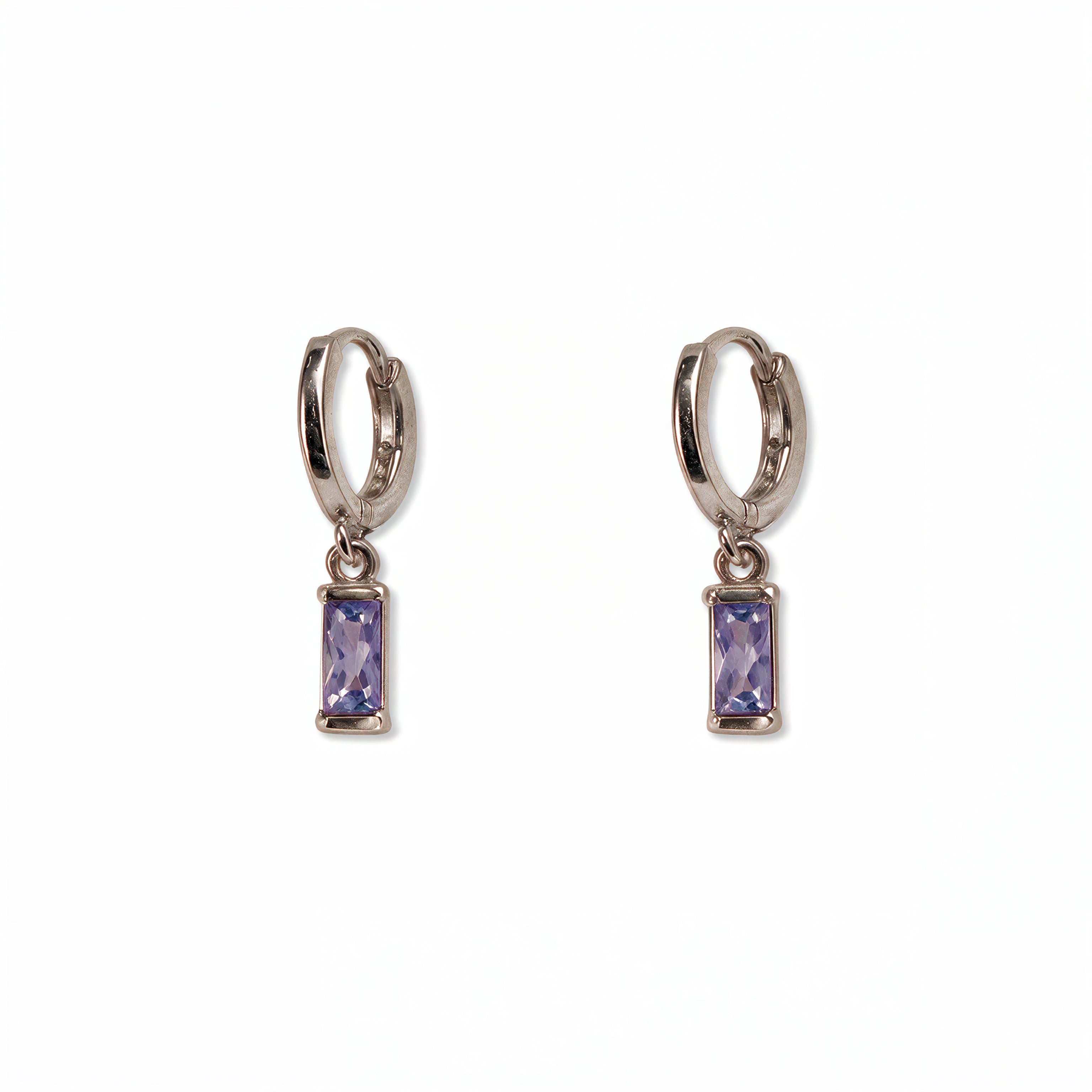 A pair of June Birthstone Lavender Cubic Zirconia Baguette Earrings by Skōsh Jewelry, featuring small sterling silver huggie hoops, each with a rectangular light purple baguette stone dangling below, displayed against a white background.
