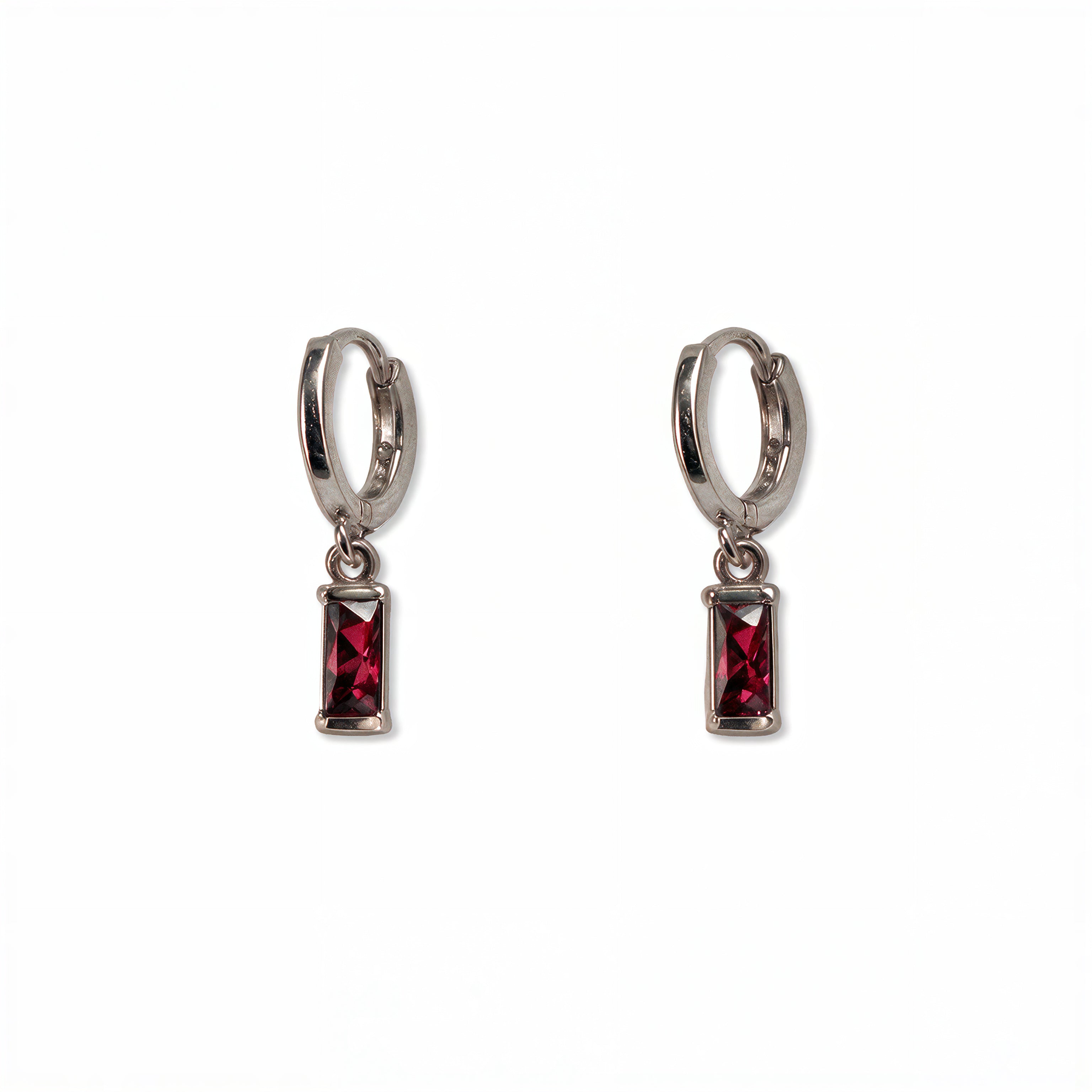 A pair of July Birthstone Ruby Cubic Zirconia Baguette Earrings by Skōsh Jewelry, featuring small sterling silver huggie hoops, each with a rectangular red baguette stone dangling below, displayed against a white background.