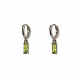 A pair of August Birthstone Peridot Cubic Zirconia Baguette Earrings by Skōsh Jewelry, featuring small sterling silver huggie hoops, each with a rectangular light green baguette stone dangling below, displayed against a white background.