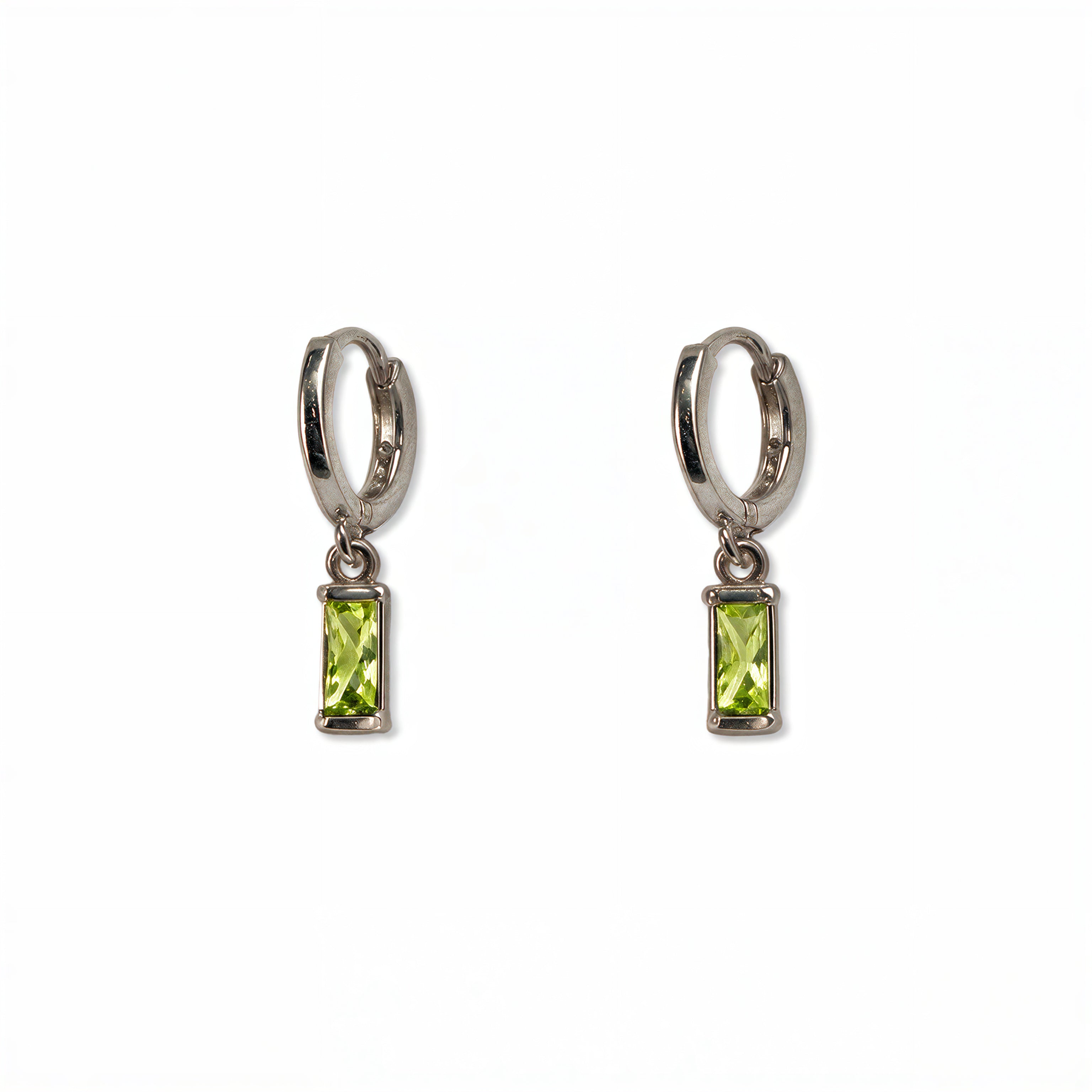 A pair of August Birthstone Peridot Cubic Zirconia Baguette Earrings by Skōsh Jewelry, featuring small sterling silver huggie hoops, each with a rectangular light green baguette stone dangling below, displayed against a white background.