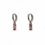 A pair of October Birthstone Pink Cubic Zirconia Baguette Earrings by Skōsh Jewelry, featuring small sterling silver huggie hoops, each with a rectangular pink baguette stone dangling below, displayed against a white background.