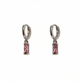 A pair of October Birthstone Pink Cubic Zirconia Baguette Earrings by Skōsh Jewelry, featuring small sterling silver huggie hoops, each with a rectangular pink baguette stone dangling below, displayed against a white background.