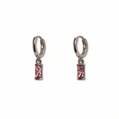 A pair of October Birthstone Pink Cubic Zirconia Baguette Earrings by Skōsh Jewelry, featuring small sterling silver huggie hoops, each with a rectangular pink baguette stone dangling below, displayed against a white background.