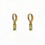 A pair of August Birthstone Peridot Cubic Zirconia Baguette Earrings by Skōsh Jewelry, featuring small gold huggie hoops, each with a rectangular light green baguette stone dangling below, displayed against a white background.