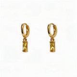 A pair of November Birthstone Citrine Cubic Zirconia Baguette Earrings by Skōsh Jewelry, featuring small gold huggie hoops, each with a rectangular yellow baguette stone dangling below, displayed against a white background.