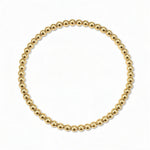 A Moonbeam 3mm Beaded Stretch Bracelet by Skōsh Jewelry, featuring a single strand of polished 3mm gold beads on a stretch cord, displayed against a white background.