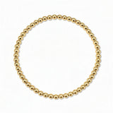 A Moonbeam 3mm Beaded Stretch Bracelet by Skōsh Jewelry, featuring a single strand of polished 3mm gold beads on a stretch cord, displayed against a white background.
