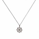 A Snowflake Pendant with White Cubic Zirconia Accent Necklace by Skōsh Jewelry, featuring a snowflake pendant accented with small clear stones on a fine sterling silver chain, displayed against a white background.