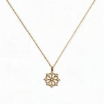 A Snowflake Pendant with White Cubic Zirconia Accent Necklace by Skōsh Jewelry, featuring a snowflake pendant accented with small clear stones on a fine gold chain, displayed against a white background.