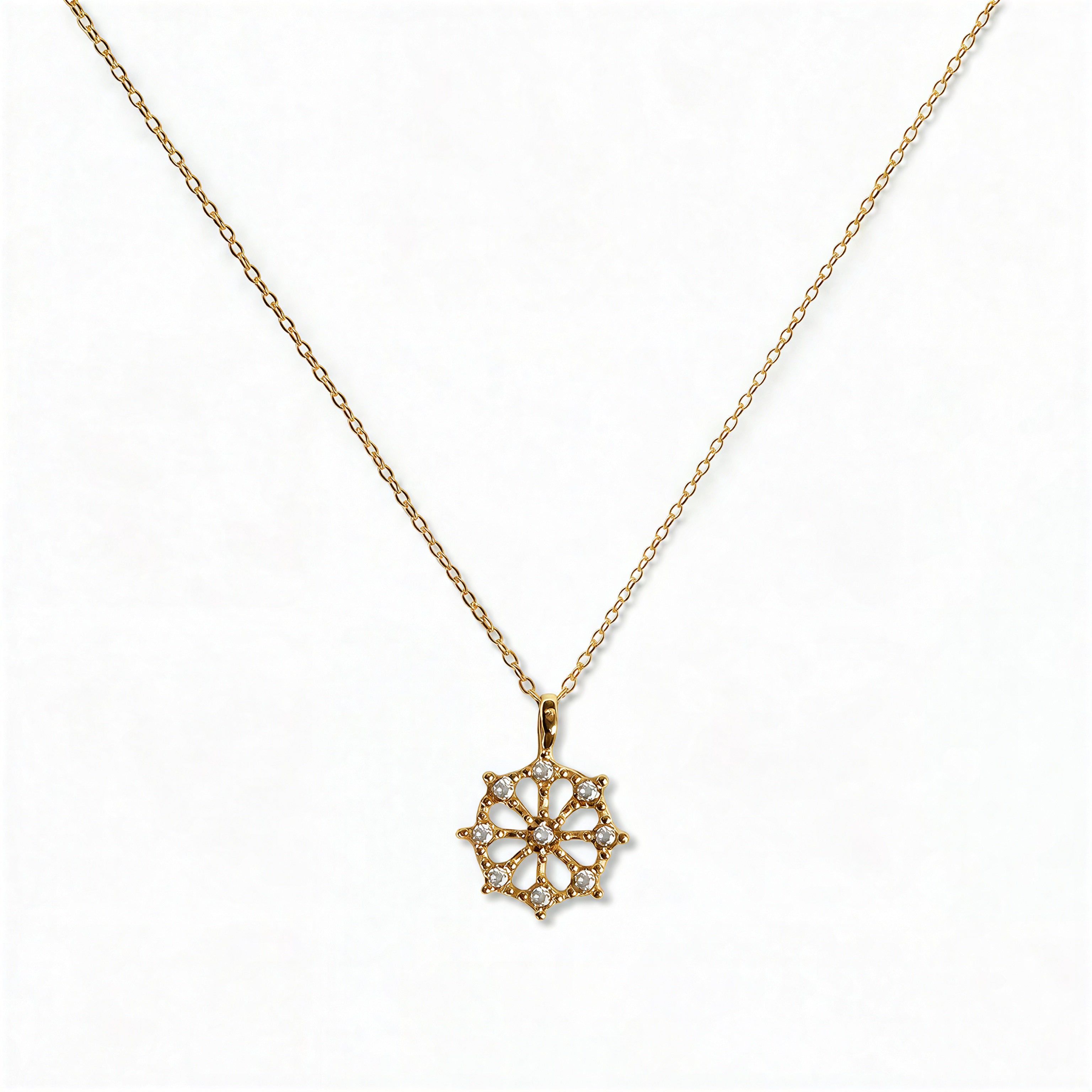A Snowflake Pendant with White Cubic Zirconia Accent Necklace by Skōsh Jewelry, featuring a snowflake pendant accented with small clear stones on a fine gold chain, displayed against a white background.