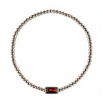 A January Birthstone Garnet Cubic Zirconia Baguette Bracelet by Skōsh Jewelry, featuring a strand of polished sterling silver beads on a stretch cord with a rectangular deep red baguette stone at the center, displayed against a white background.