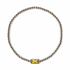 A November Birthstone Citrine Cubic Zirconia Baguette Bracelet by Skōsh Jewelry, featuring a strand of polished sterling silver beads on a stretch cord with a rectangular yellow baguette stone at the center, displayed against a white background.