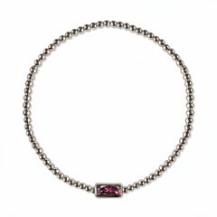 A February Birthstone Amethyst Cubic Zirconia Baguette Bracelet by Skōsh Jewelry, featuring a strand of polished sterling silver beads on a stretch cord with a rectangular purple baguette stone at the center, displayed against a white background.