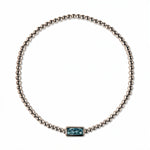 A March Birthstone Light Sapphire Cubic Zirconia Baguette Bracelet by Skōsh Jewelry, featuring a strand of polished sterling silver beads on a stretch cord with a rectangular light blue baguette stone at the center, displayed against a white background.