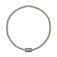 An April Birthstone White Cubic Zirconia Baguette Bracelet by Skōsh Jewelry, featuring a strand of polished sterling silver beads on a stretch cord with a rectangular clear baguette stone at the center, displayed against a white background.