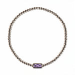 A June Birthstone Lavender Cubic Zirconia Baguette Bracelet by Skōsh Jewelry, featuring a strand of polished sterling silver beads on a stretch cord with a rectangular light purple baguette stone at the center, displayed against a white background.