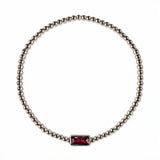 A July Birthstone Ruby Cubic Zirconia Baguette Bracelet by Skōsh Jewelry, featuring a strand of polished sterling silver beads on a stretch cord with a rectangular red baguette stone at the center, displayed against a white background.