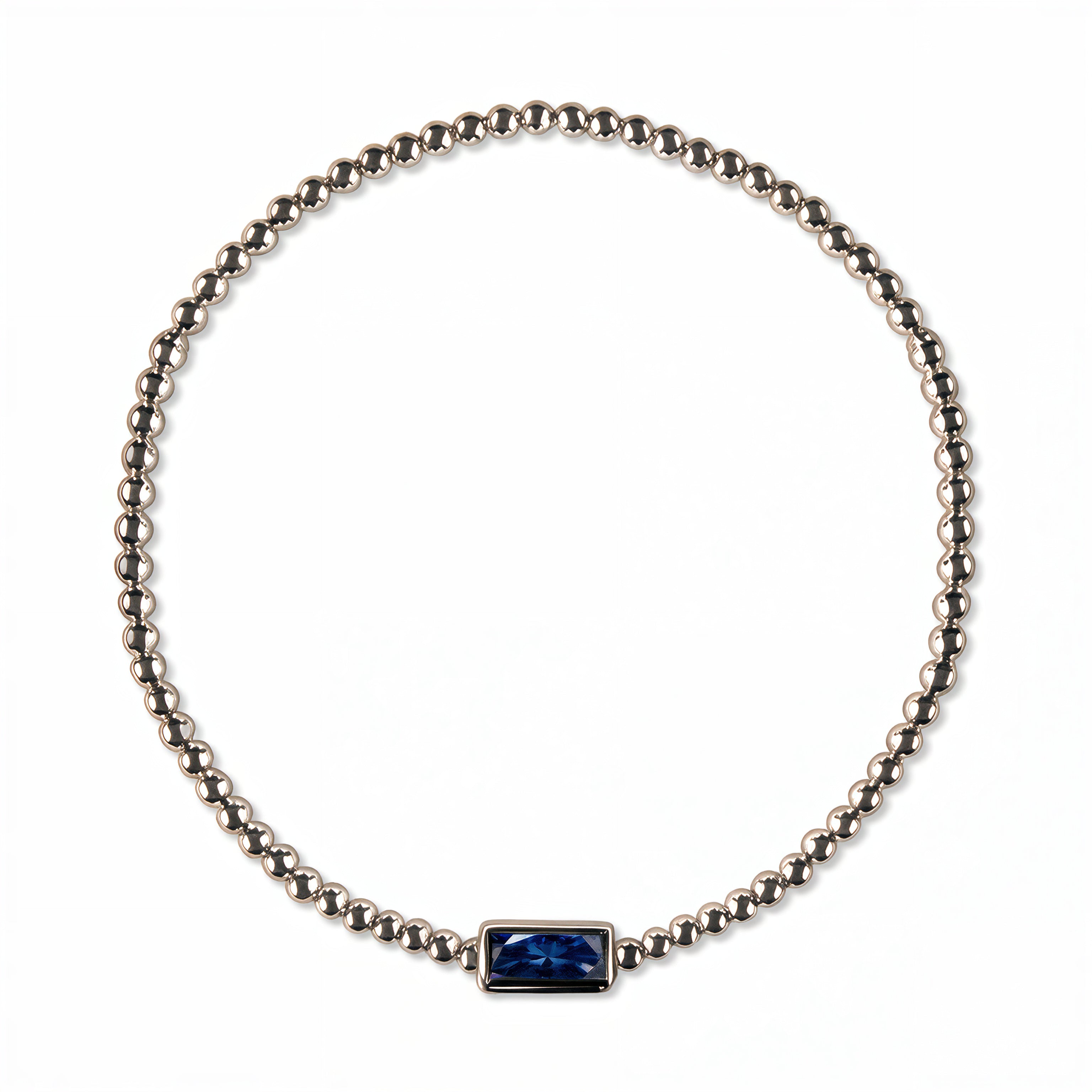 A September Birthstone Sapphire Cubic Zirconia Baguette Bracelet by Skōsh Jewelry, featuring a strand of polished sterling silver beads on a stretch cord with a rectangular deep blue baguette stone at the center, displayed against a white background.