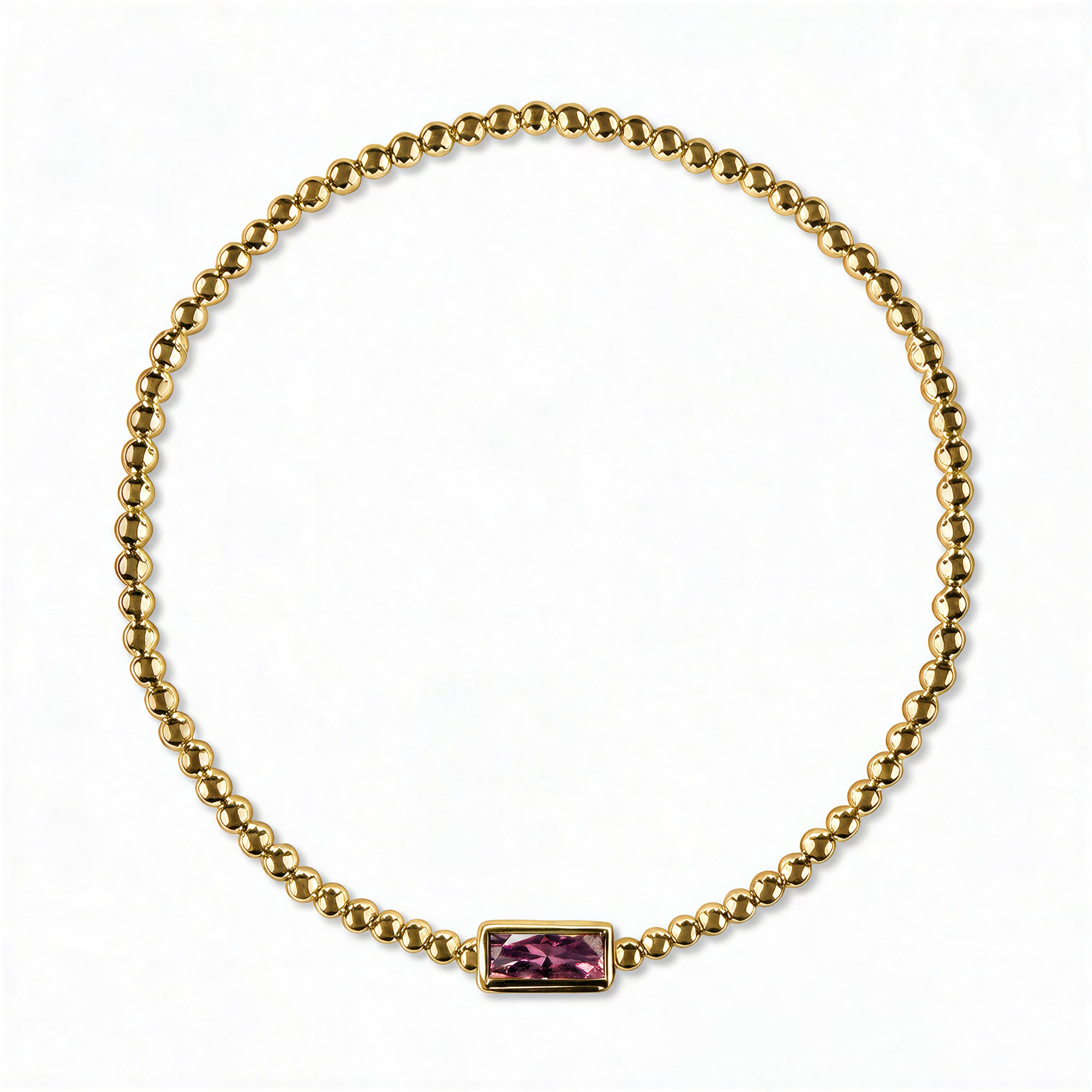 A February Birthstone Amethyst Cubic Zirconia Baguette Bracelet by Skōsh Jewelry, featuring a strand of polished gold beads on a stretch cord with a rectangular purple baguette stone at the center, displayed against a white background.
