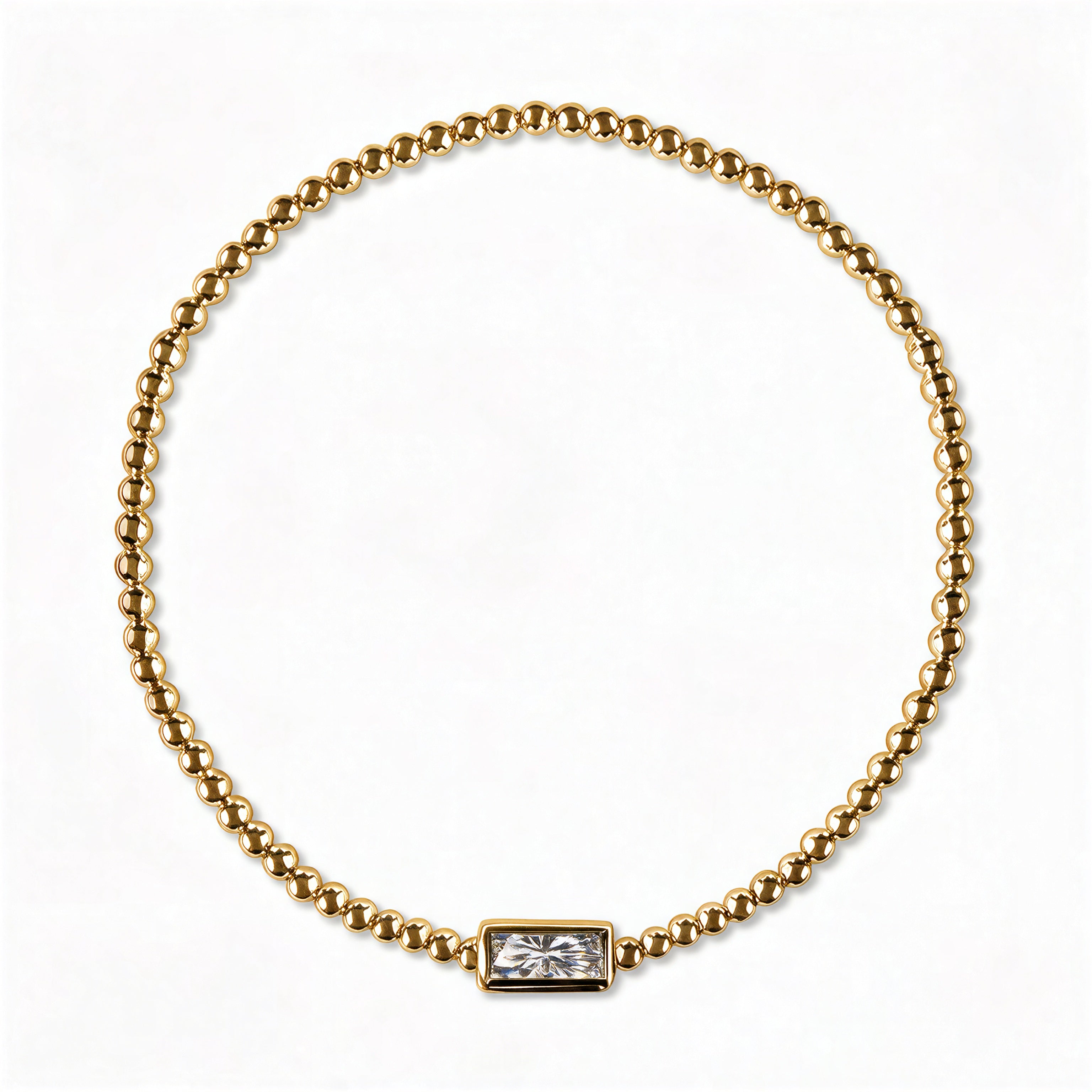 An April Birthstone White Cubic Zirconia Baguette Bracelet by Skōsh Jewelry, featuring a strand of polished gold beads on a stretch cord with a rectangular clear baguette stone at the center, displayed against a white background.