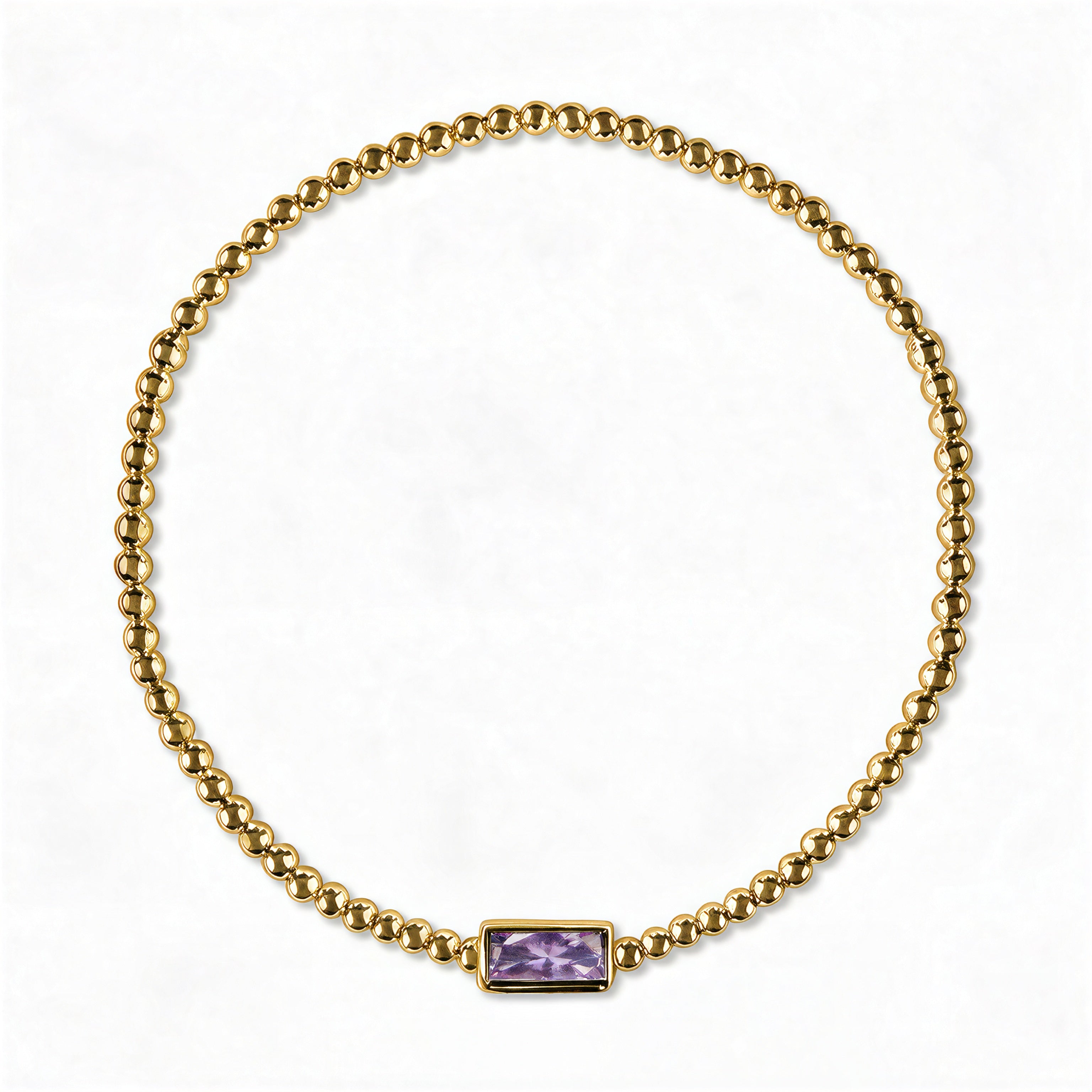 A June Birthstone Lavender Cubic Zirconia Baguette Bracelet by Skōsh Jewelry, featuring a strand of polished gold beads on a stretch cord with a rectangular light purple baguette stone at the center, displayed against a white background.