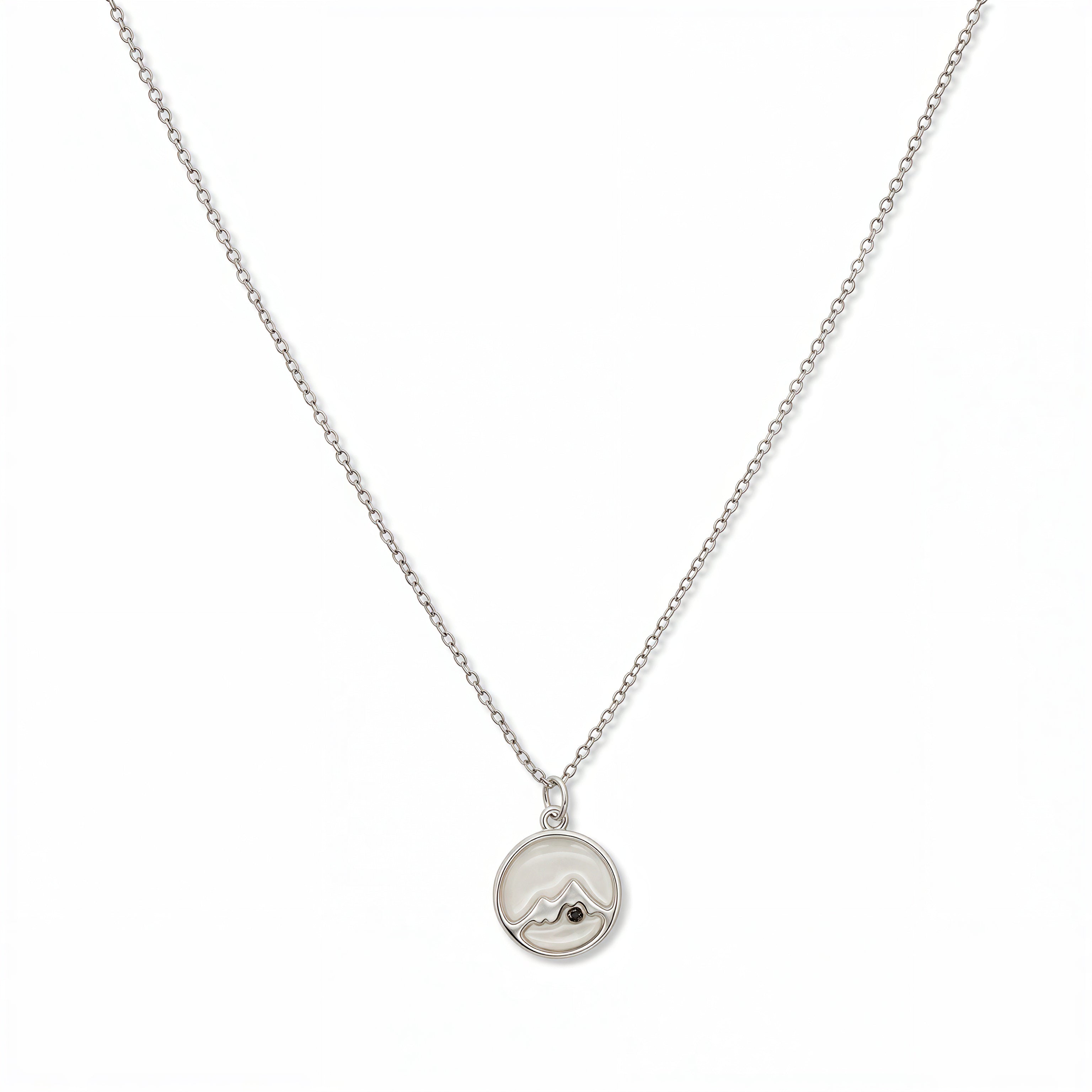 A Mustard Seed Pendant Necklace by Skōsh Jewelry, featuring a small round pendant with a mustard seed set beneath a mountain outline on a fine sterling silver chain, displayed against a white background.