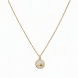 A Mustard Seed Pendant Necklace by Skōsh Jewelry, featuring a small round pendant with a mustard seed set beneath a mountain outline on a fine gold chain, displayed against a white background.