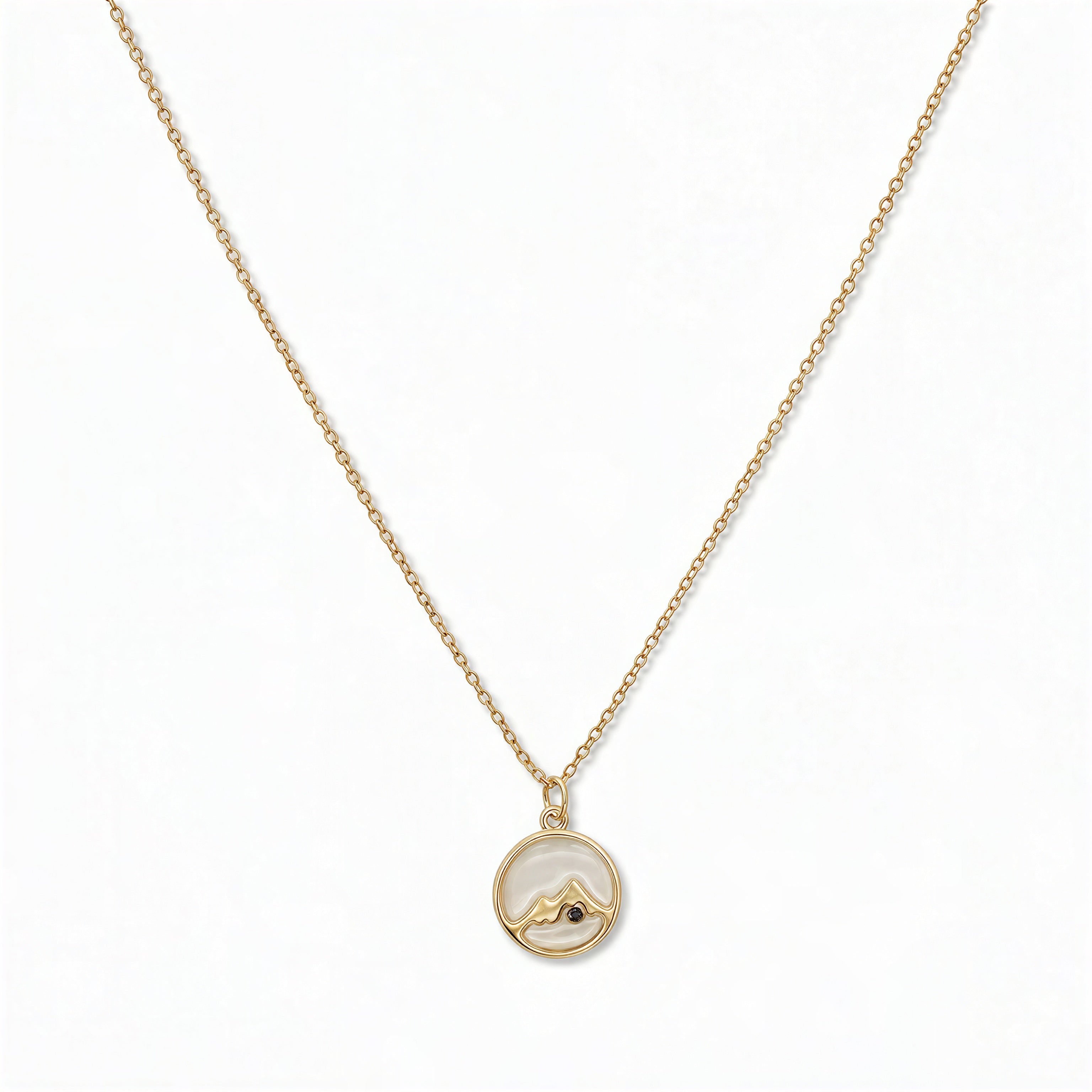 A Mustard Seed Pendant Necklace by Skōsh Jewelry, featuring a small round pendant with a mustard seed set beneath a mountain outline on a fine gold chain, displayed against a white background.