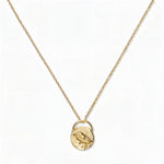 A Loved & Never Alone Bird Pendant Necklace by Skōsh Jewelry, featuring a rounded pendant with a cutout of a small bird on a fine gold chain, displayed against a white background.