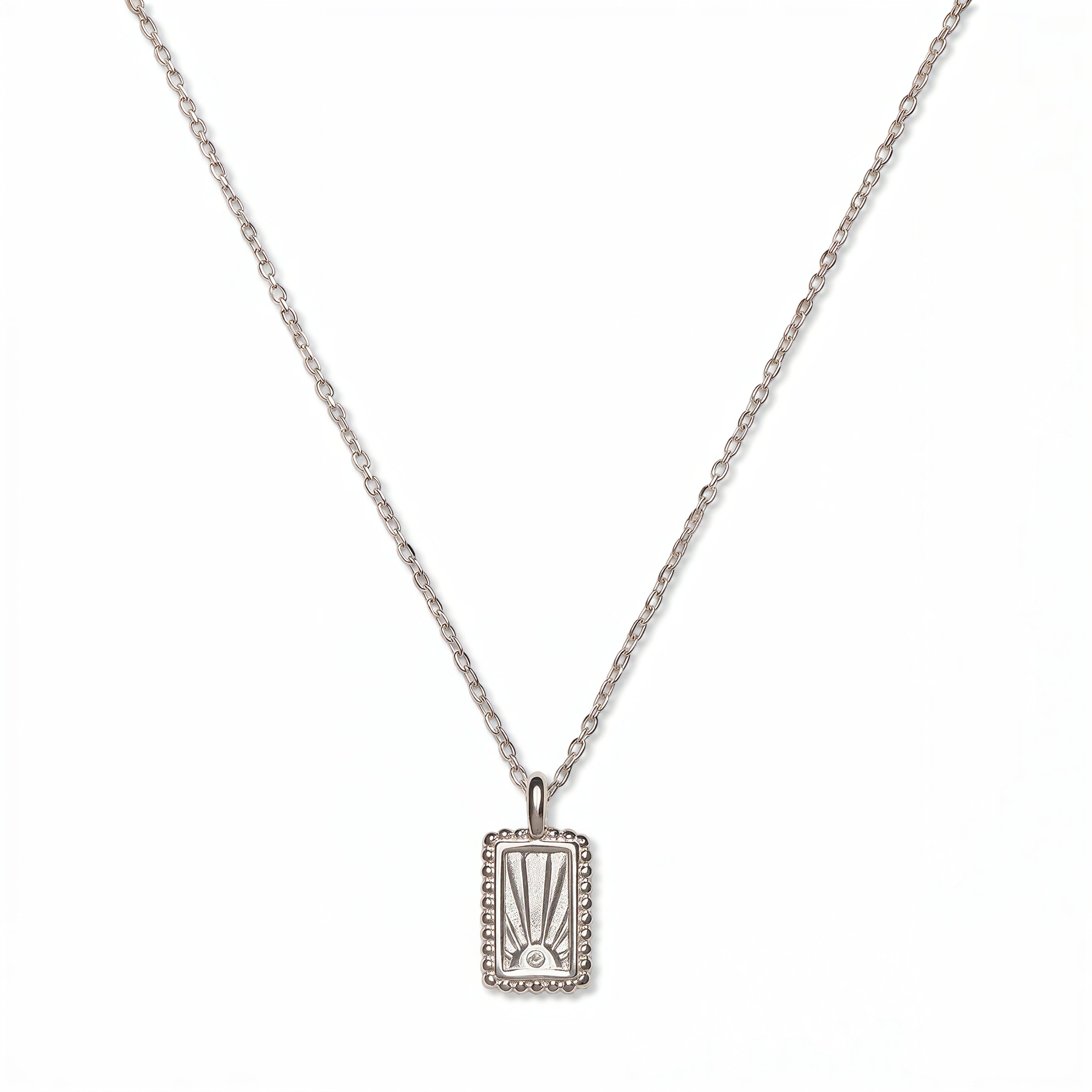 A New Dawn Sunrise Picture Frame Pendant Necklace by Skōsh Jewelry, featuring a small rectangular frame pendant engraved with a rising sun on a fine sterling silver chain, displayed against a white background.