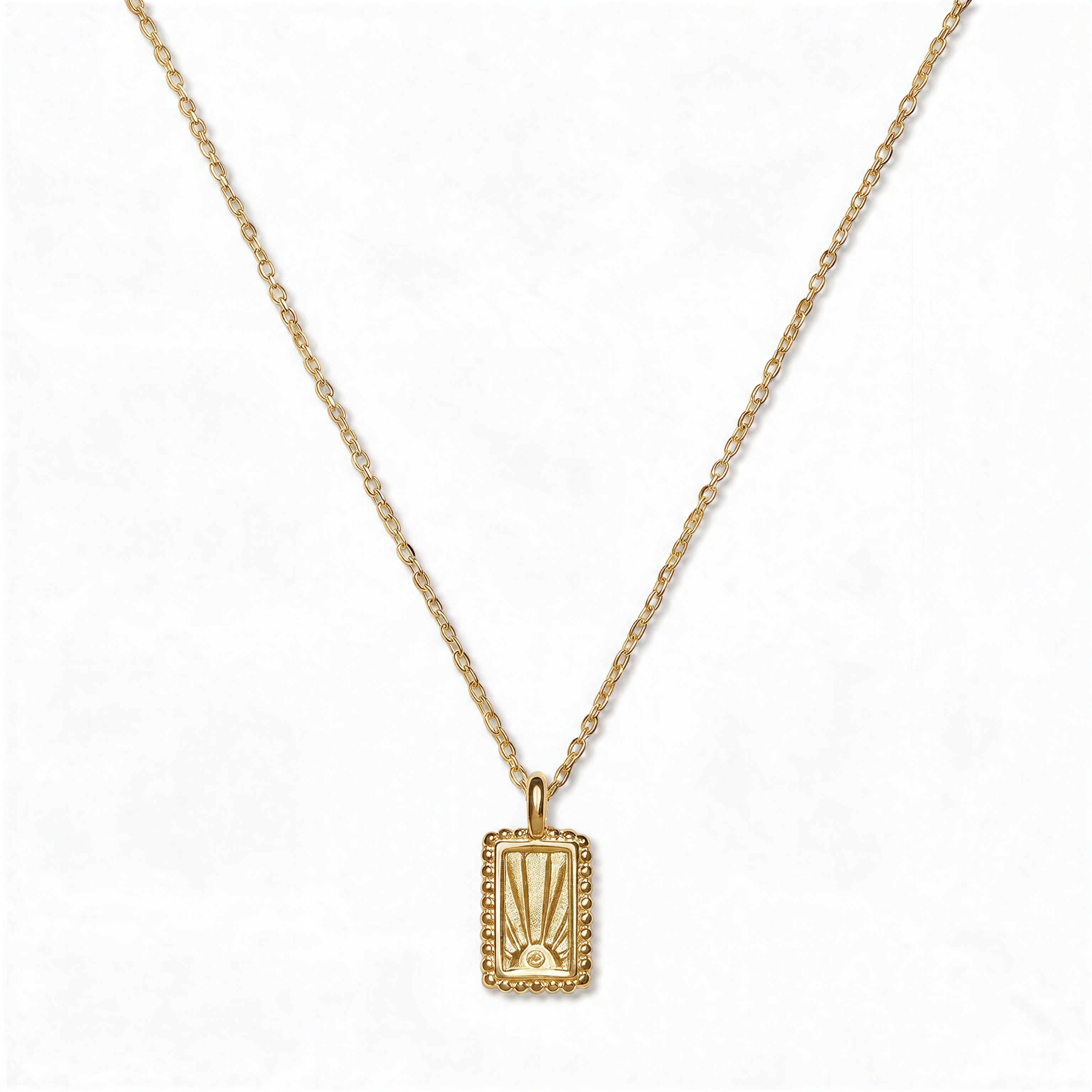 A New Dawn Sunrise Picture Frame Pendant Necklace by Skōsh Jewelry, featuring a small rectangular frame pendant engraved with a rising sun on a fine gold chain, displayed against a white background.