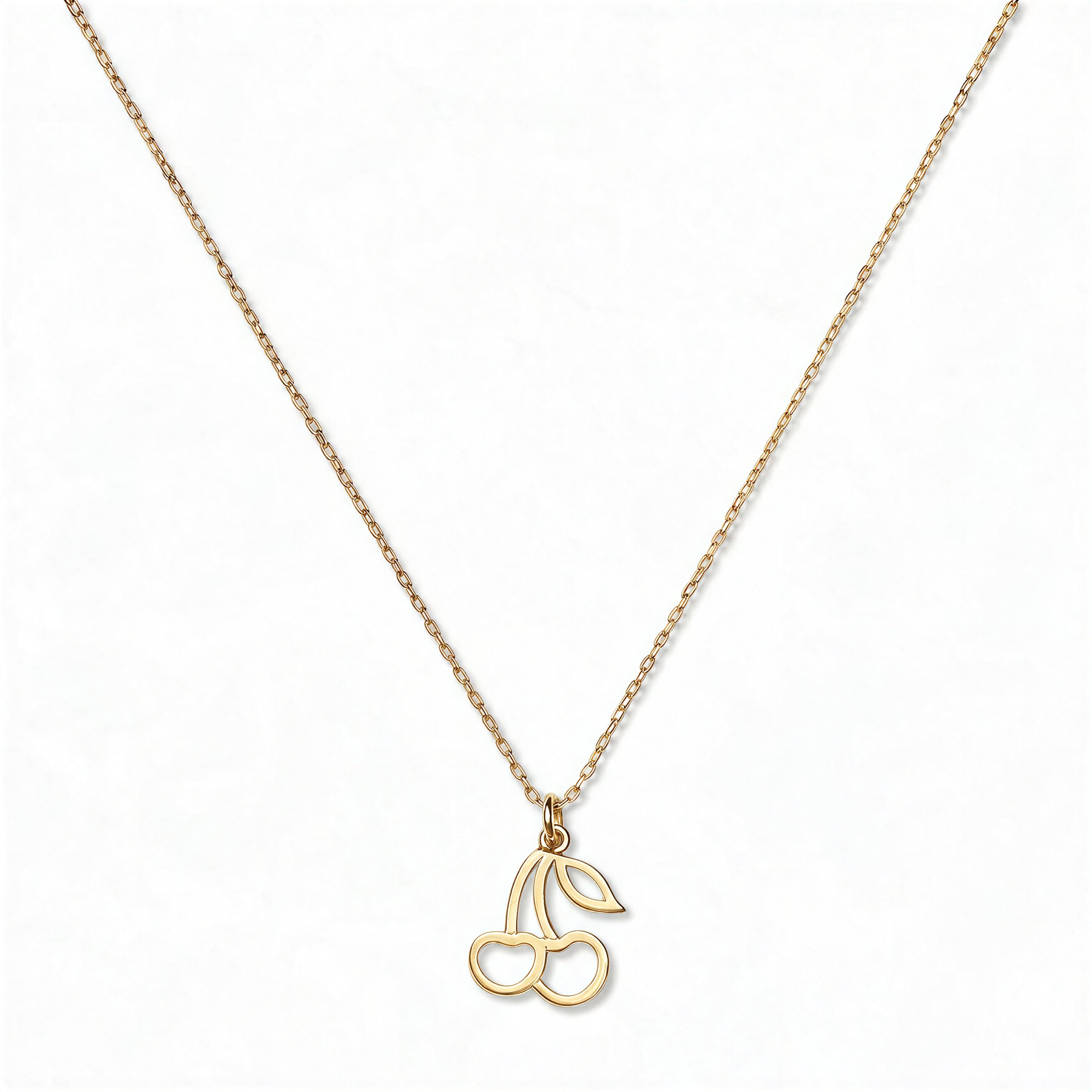 A Double Cherry Pendant Necklace by Skōsh Jewelry, featuring two small cherries joined at the stem on a fine gold chain, displayed against a white background.