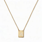 An Engraved Initial Necklace Letter A by Skōsh Jewelry, featuring a small rectangular tag engraved with the letter A on a fine gold chain, displayed against a white background.