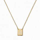 An Engraved Initial Necklace Letter A by Skōsh Jewelry, featuring a small rectangular tag engraved with the letter A on a fine gold chain, displayed against a white background.