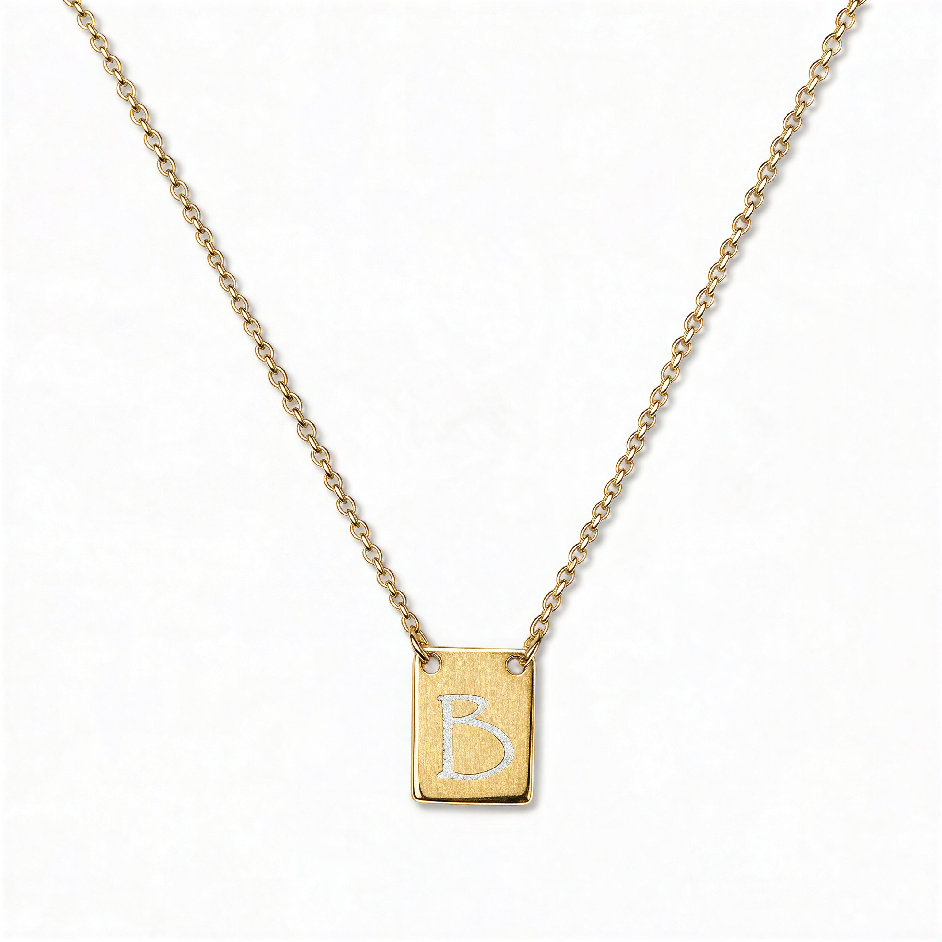 An Engraved Initial Necklace Letter B by Skōsh Jewelry, featuring a small rectangular tag engraved with the letter B on a fine gold chain, displayed against a white background.