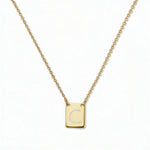 An Engraved Initial Necklace Letter C by Skōsh Jewelry, featuring a small rectangular tag engraved with the letter C on a fine gold chain, displayed against a white background.