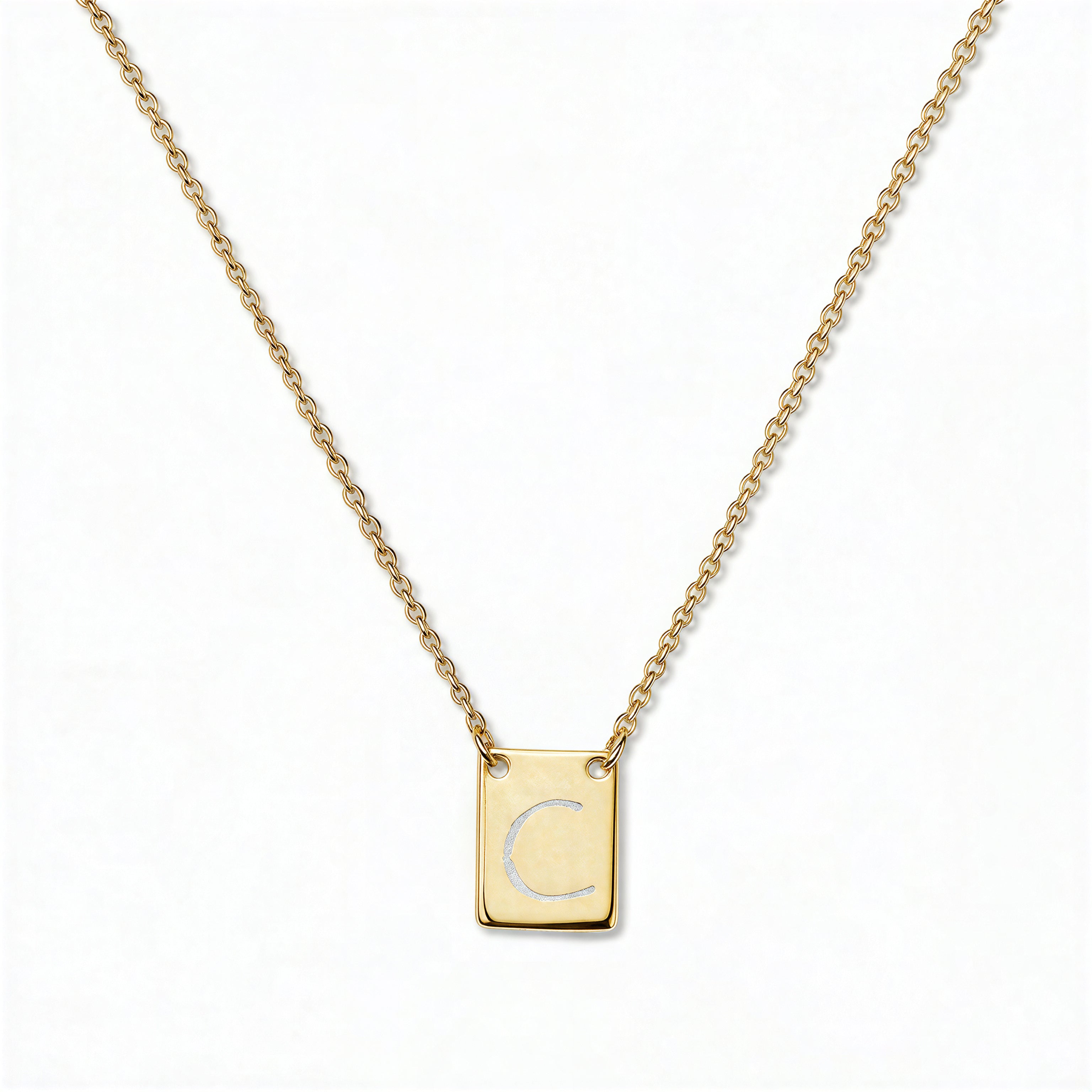An Engraved Initial Necklace Letter C by Skōsh Jewelry, featuring a small rectangular tag engraved with the letter C on a fine gold chain, displayed against a white background.