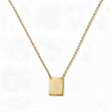 An Engraved Initial Necklace Letter D by Skōsh Jewelry, featuring a small rectangular tag engraved with the letter D on a fine gold chain, displayed against a white background.