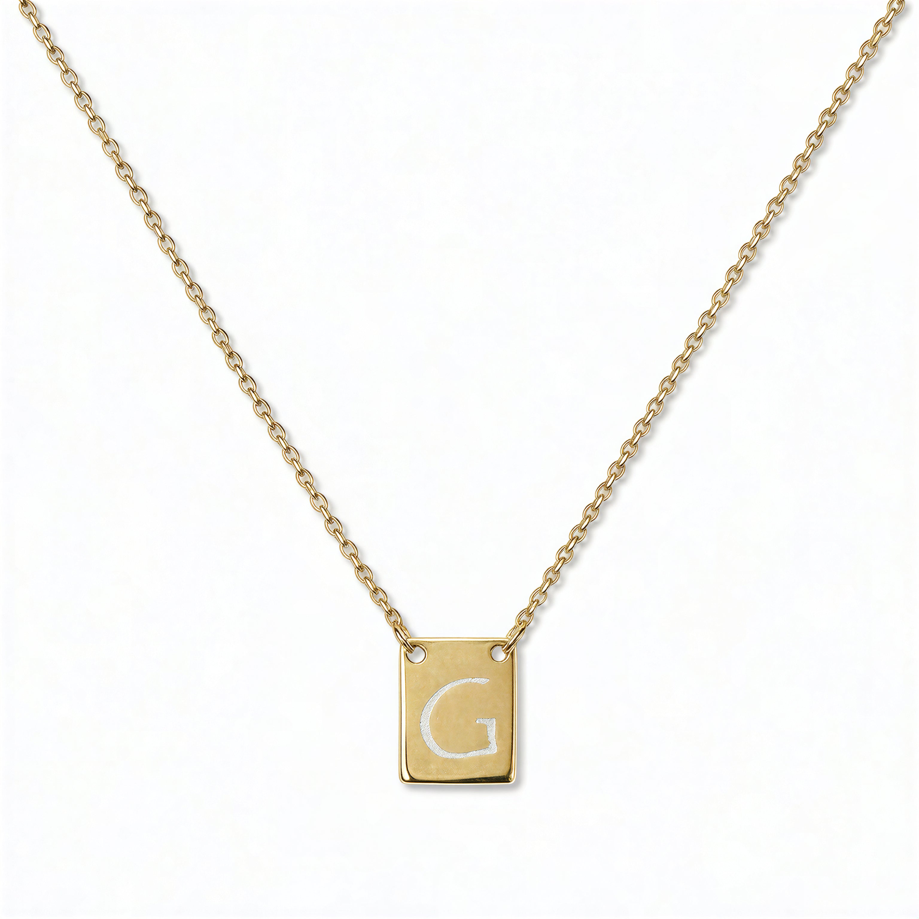 An Engraved Initial Necklace Letter G by Skōsh Jewelry, featuring a small rectangular tag engraved with the letter G on a fine gold chain, displayed against a white background.