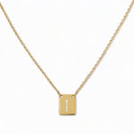 An Engraved Initial Necklace Letter I by Skōsh Jewelry, featuring a small rectangular tag engraved with the letter I on a fine gold chain, displayed against a white background.