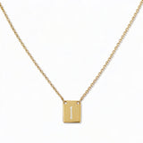 An Engraved Initial Necklace Letter I by Skōsh Jewelry, featuring a small rectangular tag engraved with the letter I on a fine gold chain, displayed against a white background.
